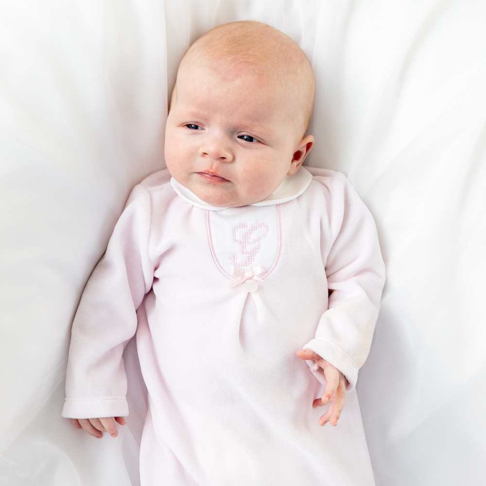 Young baby lying down wearing a pink outfit 