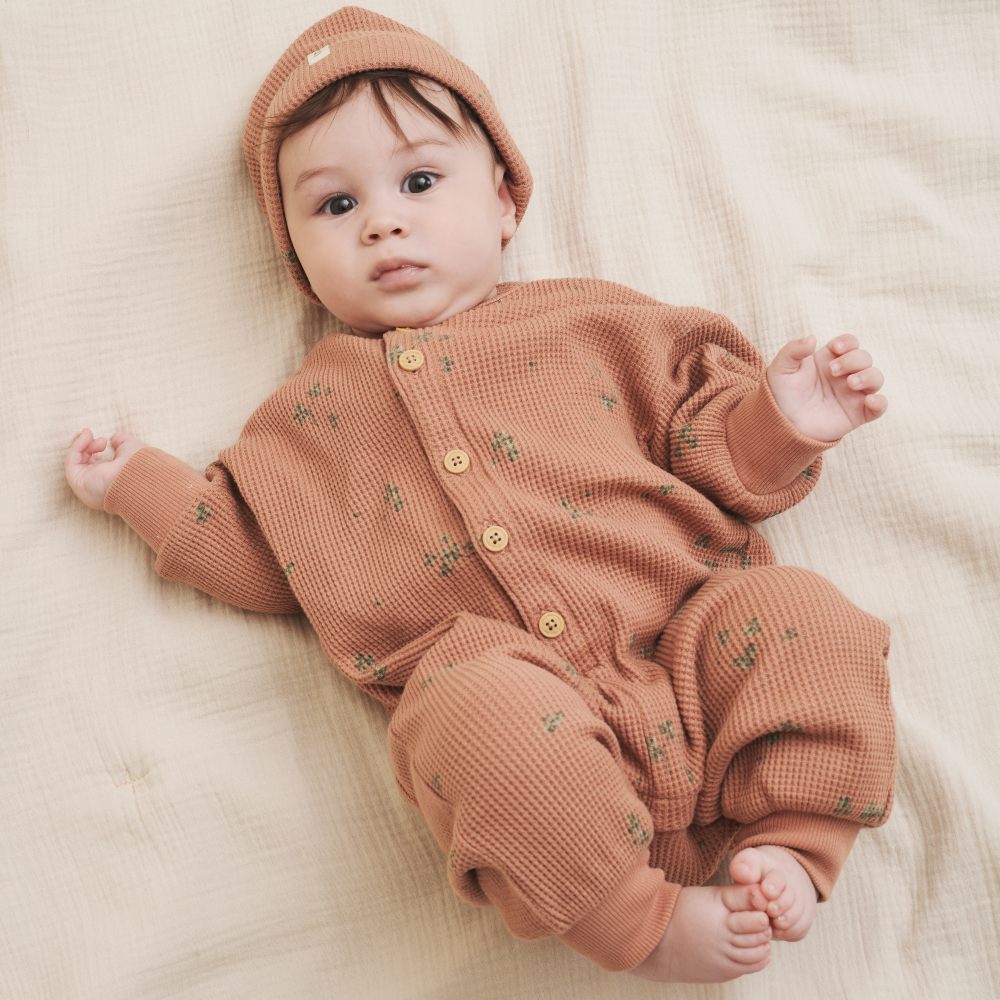 Young baby lying down wearing a hat and babygro 