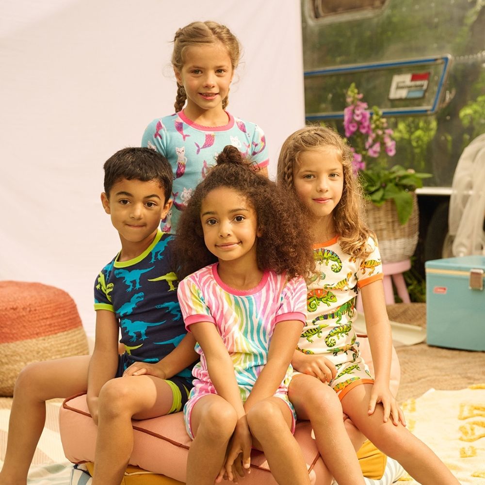 Four young children sat on a stool wearing brightly coloured shorts and T-shirts