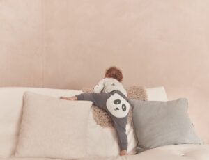 The back of a young child climbing on a sofa wearing leggings with a panda face on the bottom