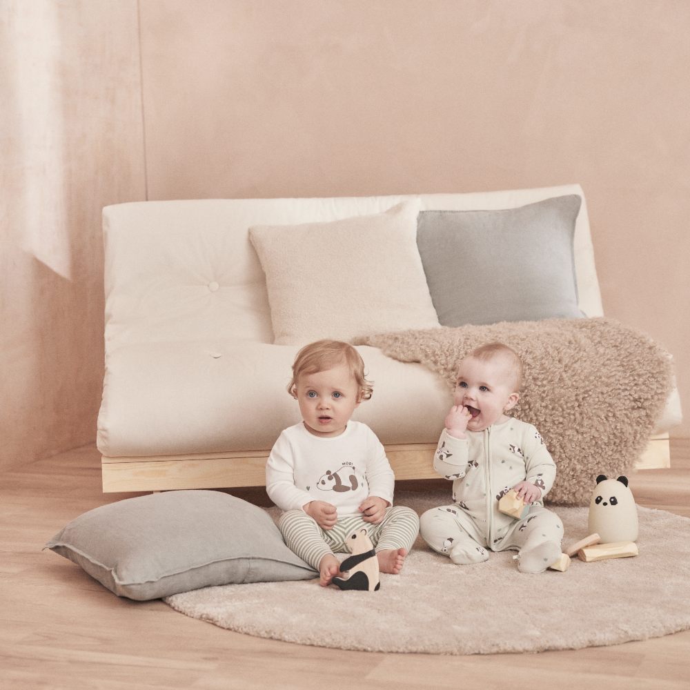 Two babies sat on the floor wearing outfits from MORI's Panda Collection