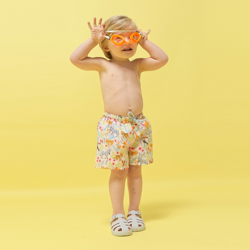 Young boy wearing swimming goggles wearing shorts and jelly shoes 