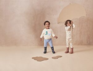 Two children with a cardboard umbrella wearing the Peppa Pig by Mori childrenswear collection