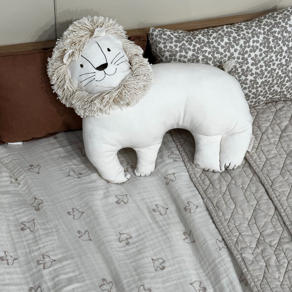 A white lion cushion on a bed 