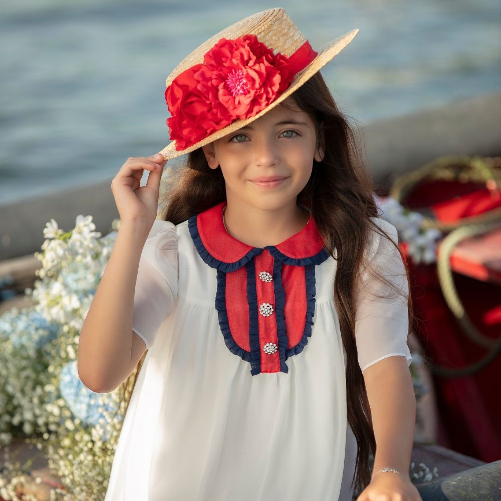 Young Girl wearing a straw hat with red flowers and a white dress 