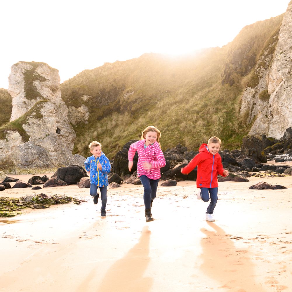 Three children running on a beach 