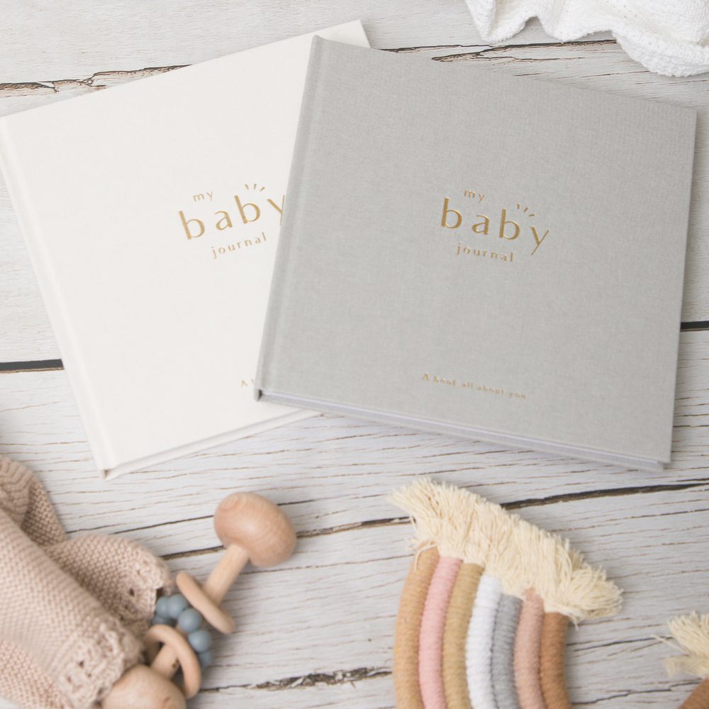 A white and grey baby journal beside children's toys 