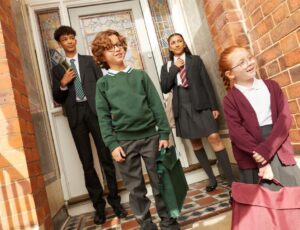 Four children in school uniform stood in a porchway