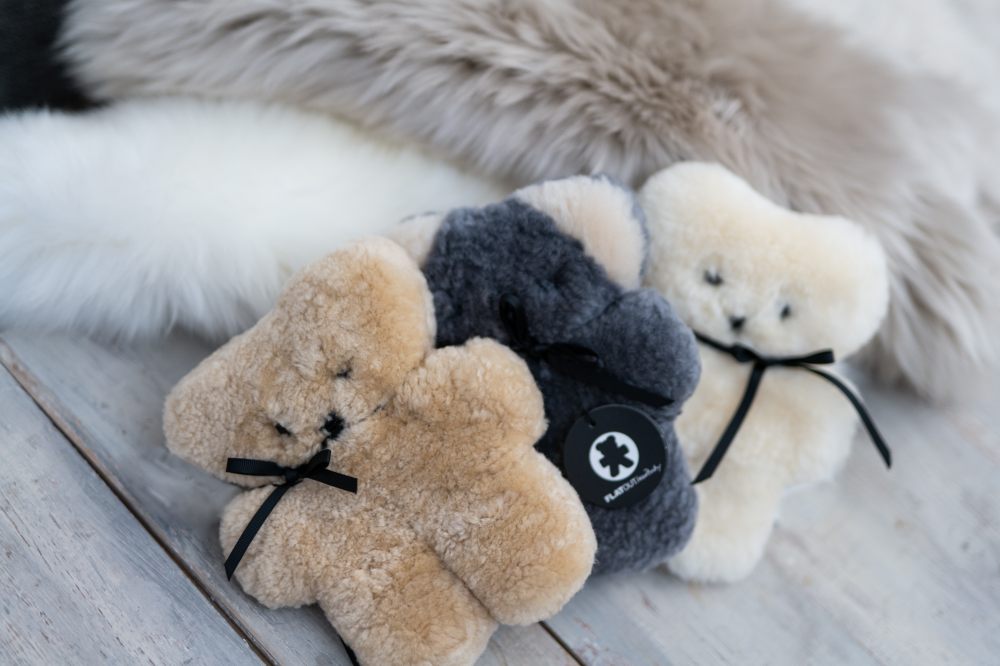 Three FLATOUT bears displayed beside sheepskin rugs 