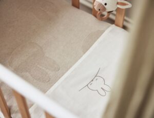A baby's cot dressed in bedding from the Jollein x Miffy collection