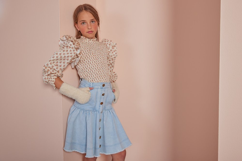 A girl stood against a wall wearing a top, gloves and a denim skirt by Petite Amalie 