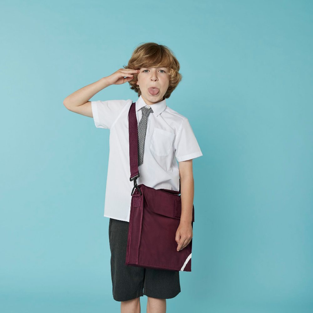 A school boy wearing a white shirt, grey shorts and a maroon school bag by Quadra