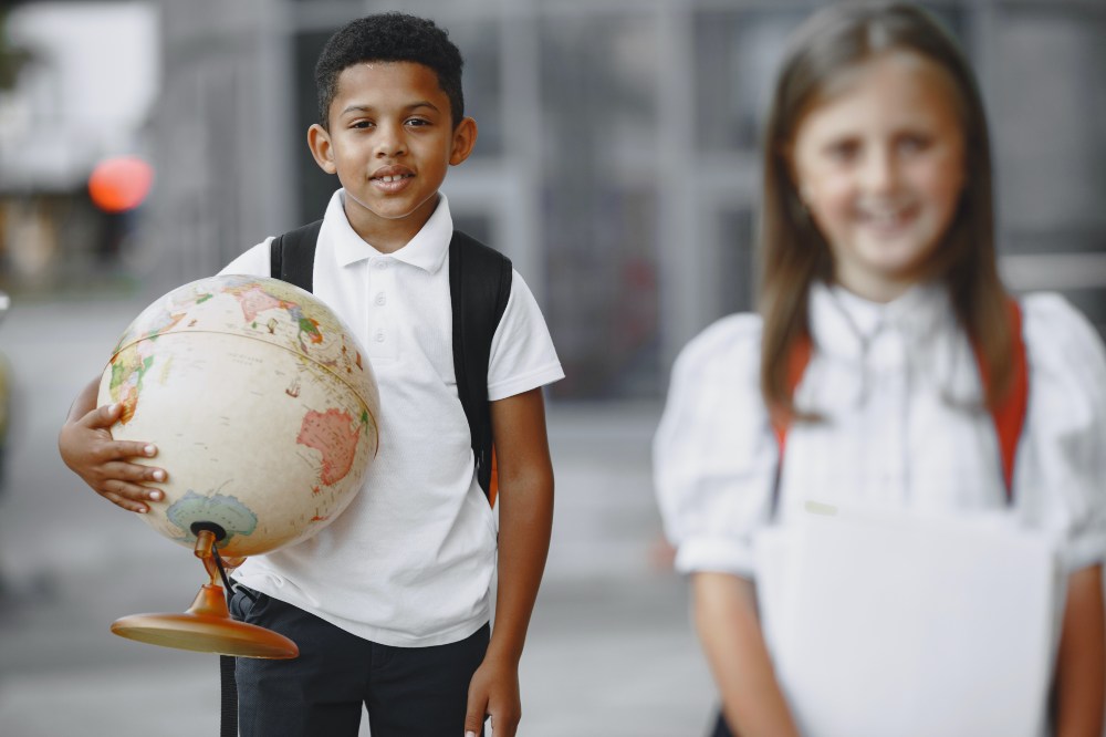 A school boy holding a world globe stood beside a school girl