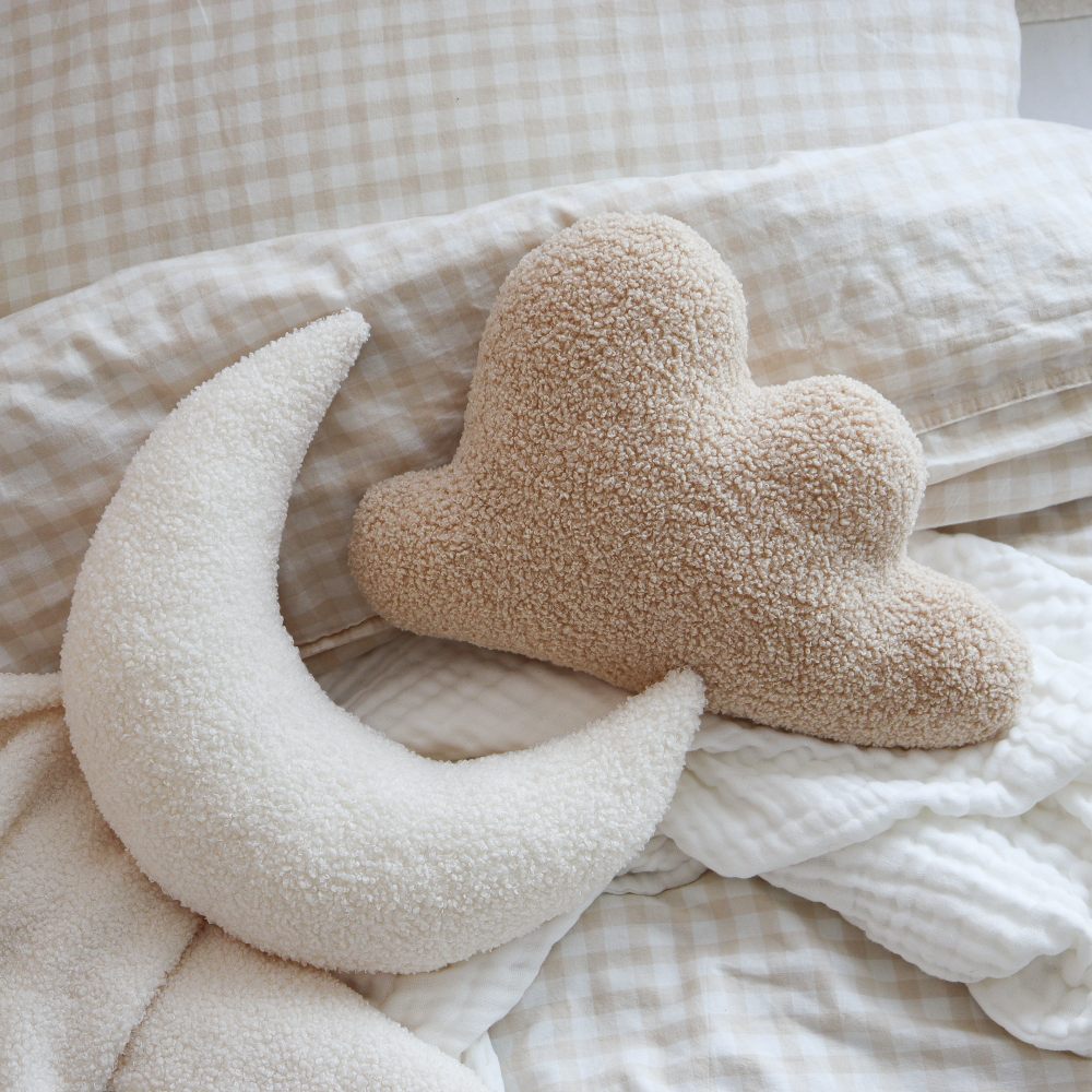 Moon and cloud shaped cushions displayed on a bed