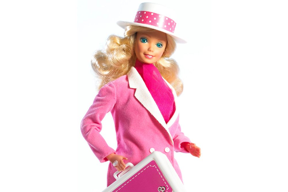A Barbie doll wearing a hat and carrying a case