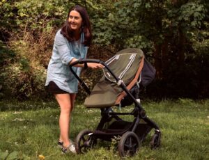 A woman stood outside with a pram covered with a sleep cover by Coperi