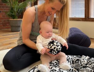 A woman sat on the floor with a baby on an Etta Loves playmat