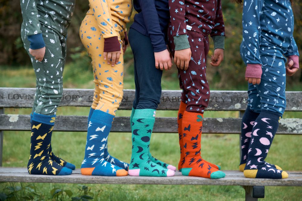 Children stood on a bench wearing Muddy Puddles' base layers and socks 