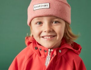 A young child wearing a pink Roarsome beanie and coat