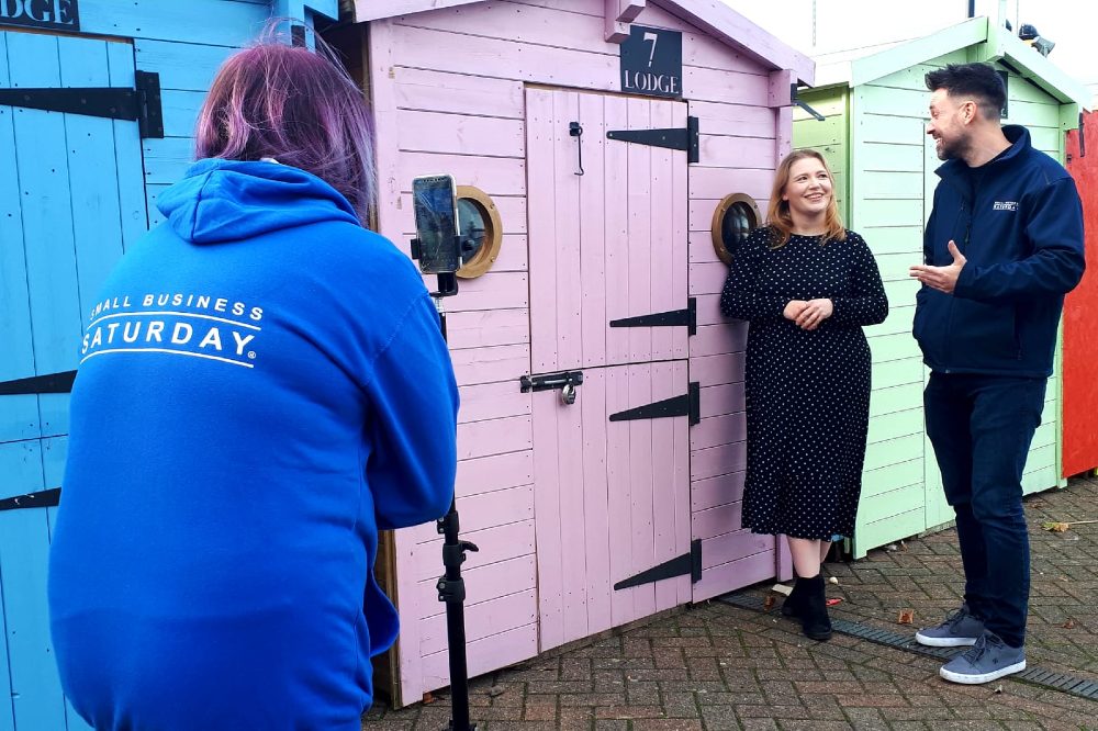 Someone filming two people doing an interview outside a pink hut for Small Business Saturday