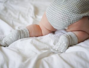 A baby's legs crawling wearing grey socks by The Little Sock Company