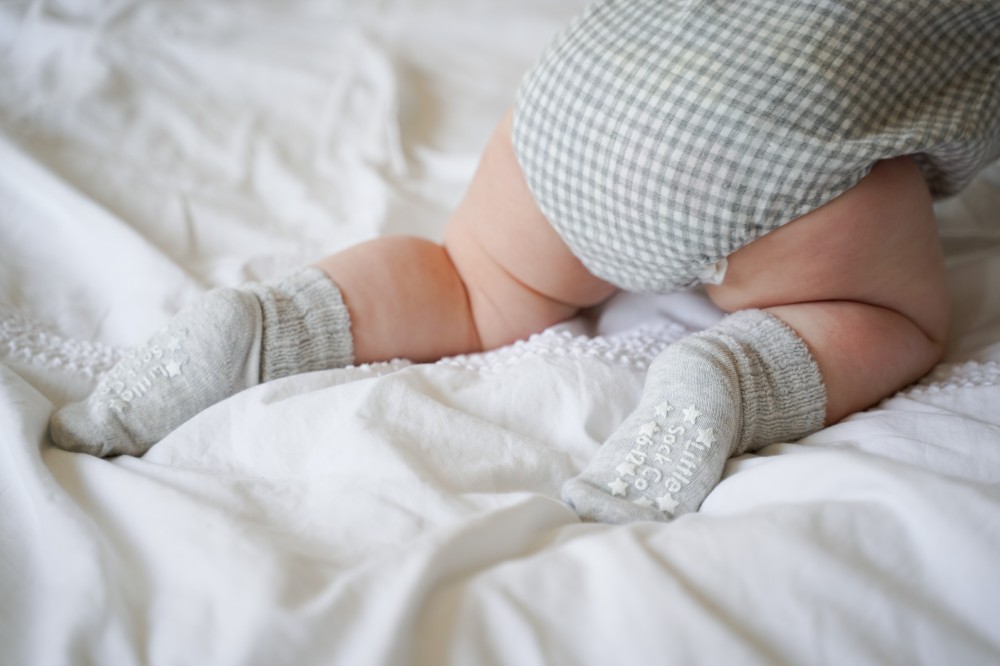 A baby's legs crawling wearing grey socks by The Little Sock Company