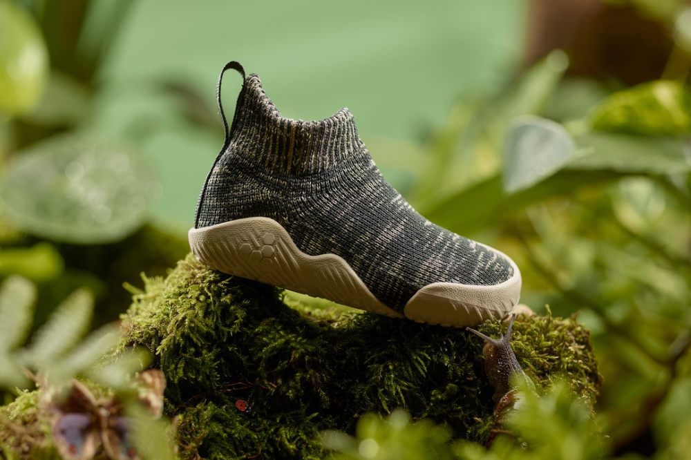 The Pluma first walker shoes by Viviobarefoot displayed outside on a moss covered log