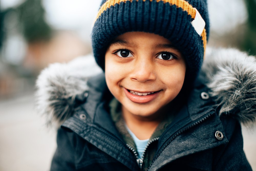 A young boy wearing a hat and winter coat