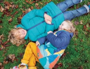 Two children lying on grass wearing winter coats