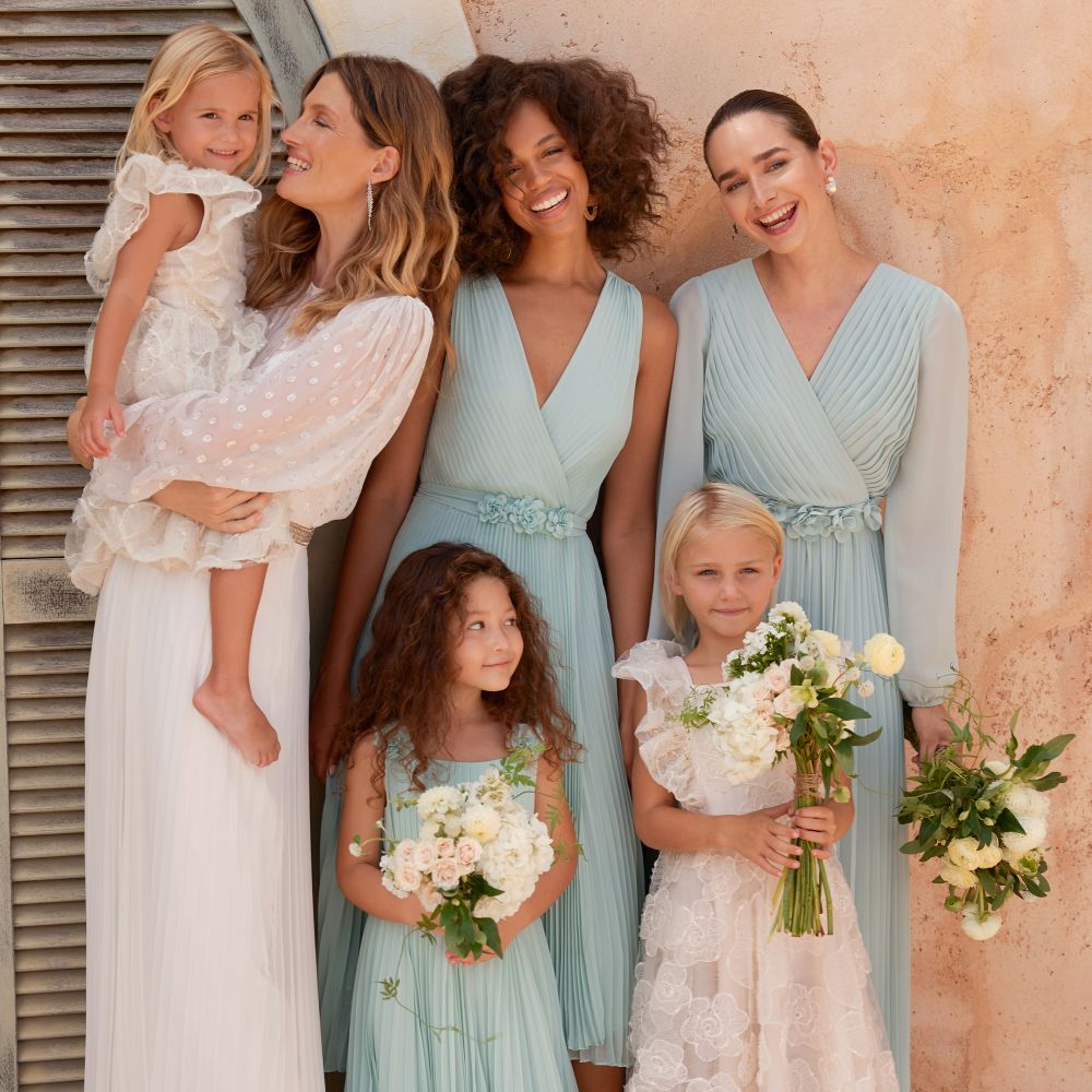 A group of woman and young girls stood outside wearing occasionwear dresses by Phase Eight 