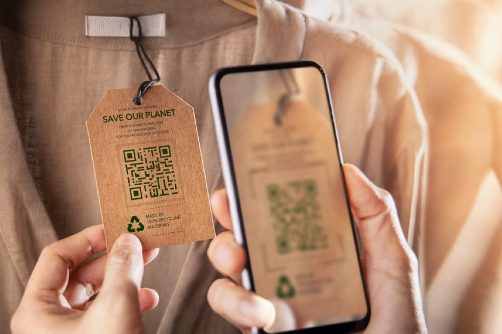 A hand scanning a QR code on a clothing label to demonstrate On 13 December, leading testing, inspection and certification company, SGS, will present a complimentary webinar for brands, retailers and manufacturers in the footwear and apparel industries titled ‘Advancing fashion accountability: the the SGS Digital Traceability Solution