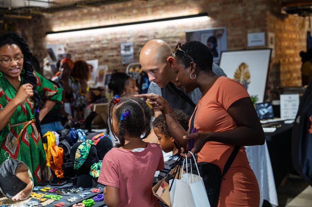 A couple with a young child looking a products on a stall 