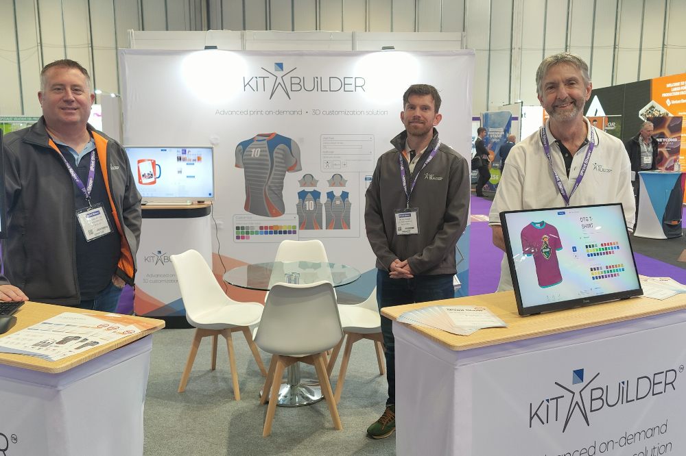 Three people from the Kit Builder team stood on a trade show stand