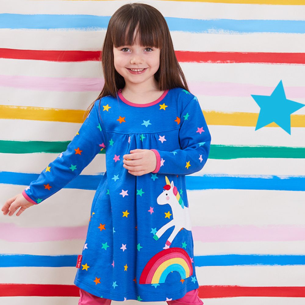 A young girl wearing a bright blue dress with a rainbow and unicorn on 