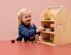 A young child playing with a wooden dolls house