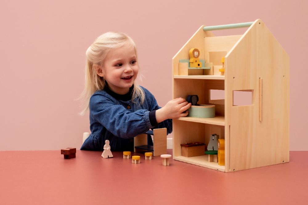 A young child playing with a wooden dolls house
