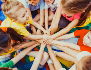 Group of children sat down holding their hands together - Child product safety: EU Decision requirements