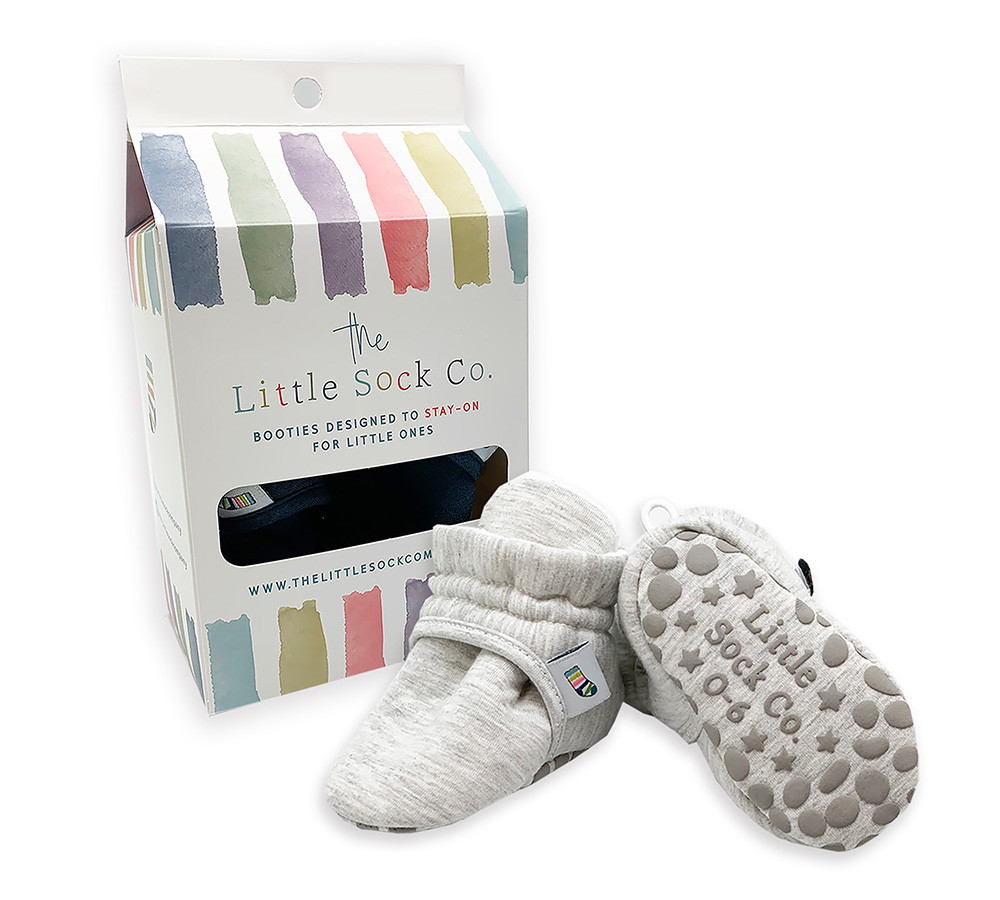 Pair of grey stay-on baby booties next to its packaging box