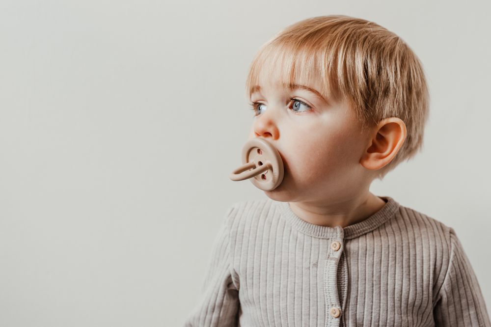 A young child with a dummy in its mouth