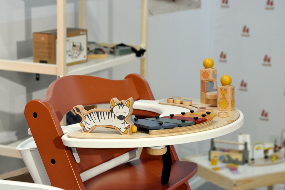 A wooden baby's highchair with wooden toys on the tray