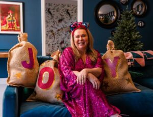 Holly Tucker MBE, founder of Holly & Co, sat on a blue sofa