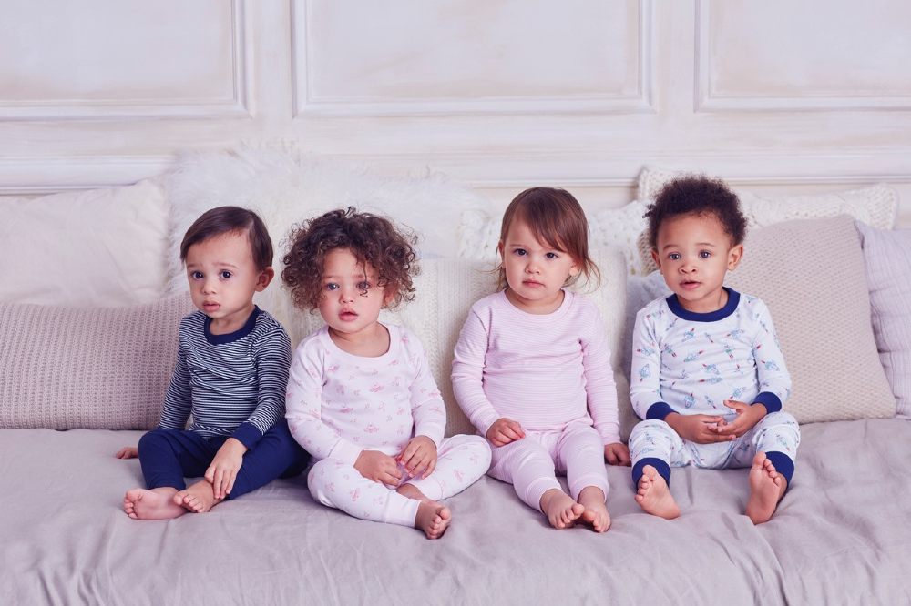 Four young child sat in a row wearing sleepwear