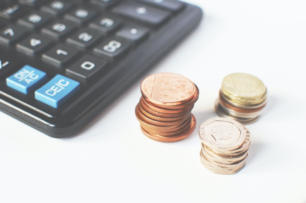 A black calculator beside piles of coins