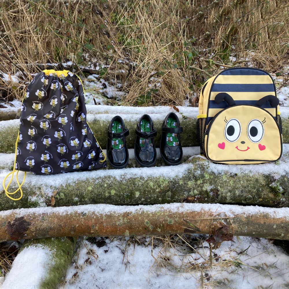 Children's school shoes and bags displayed outside on snowy logs