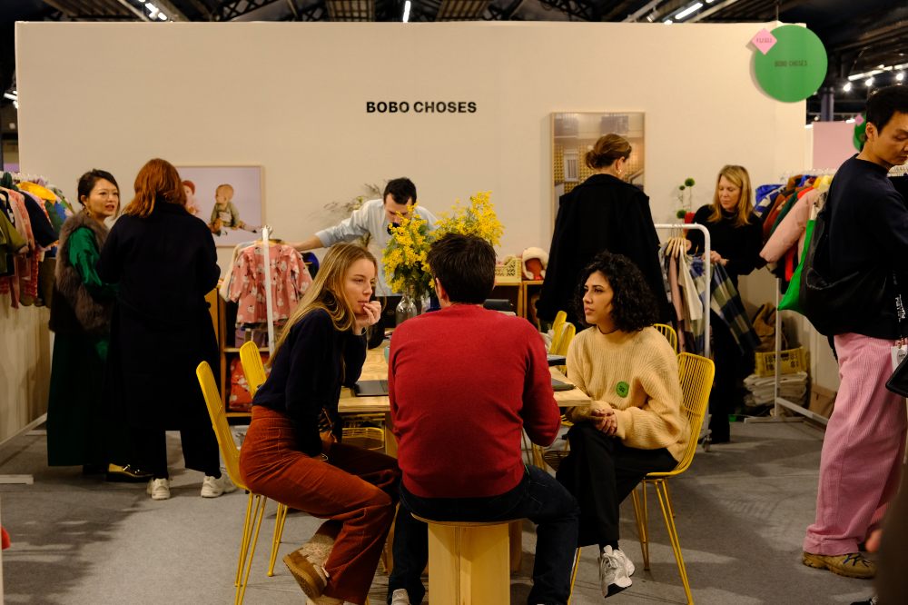 People sat at a table on a childrenswear stand at Playtime Paris