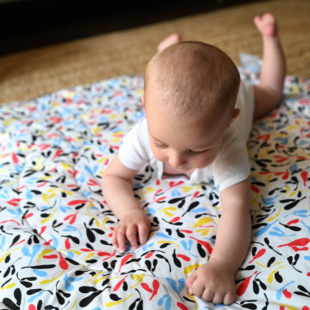 A baby crawling across a playmat on the floor