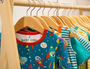 Brightly coloured children's clothes by Ducky Zebra displayed on a wooden rail at INDX Kids
