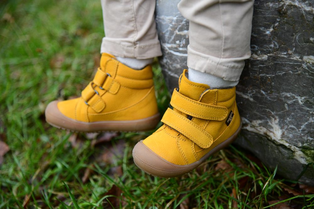 A child's feet wearing yellow shoes 