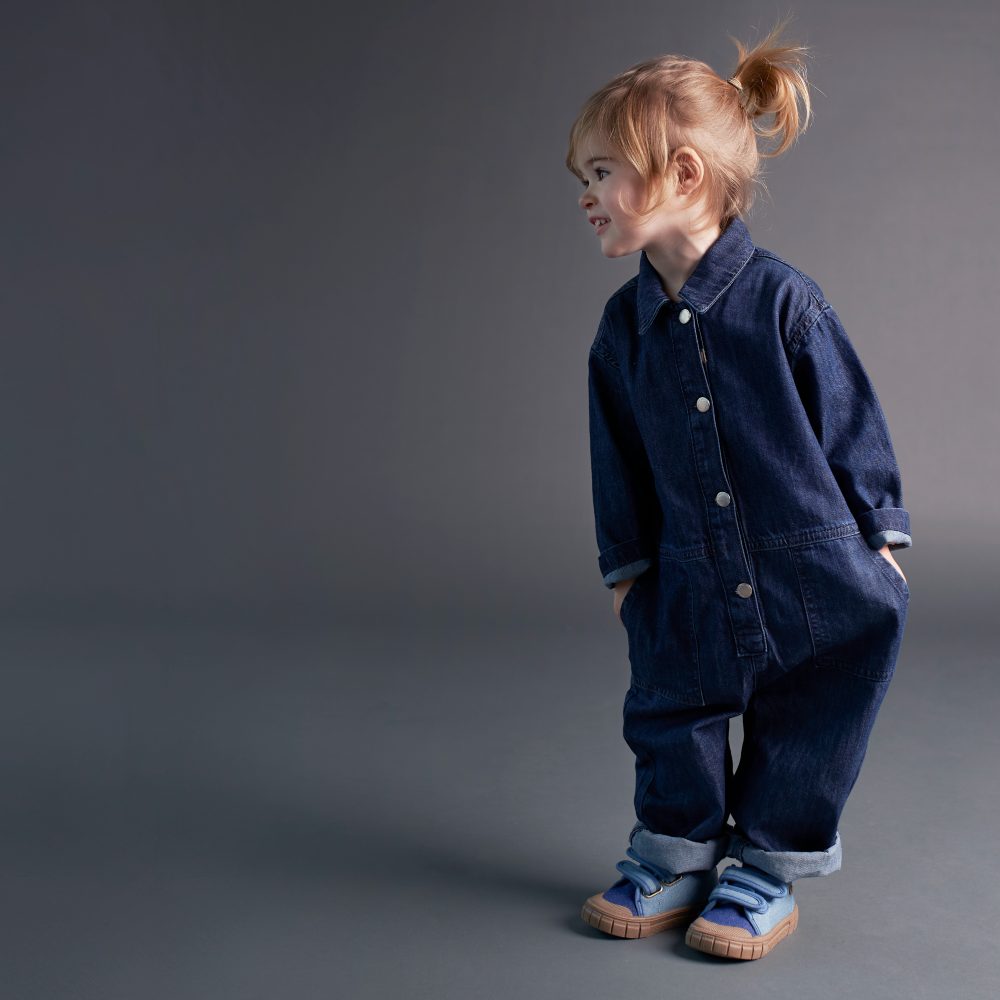 A young girl wearing a boiler suit from the KIDLY denim collection 
