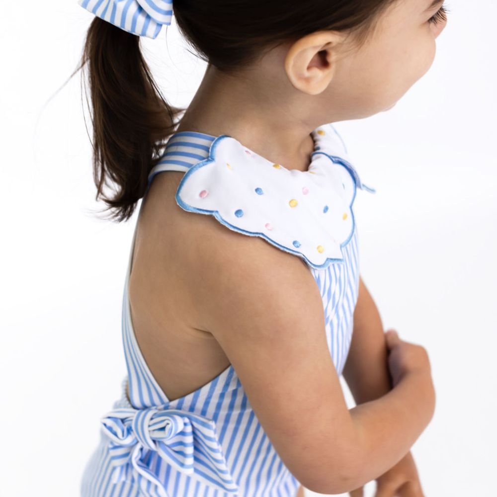 A young child wearing a blue striped swimsuit with a scalloped collar 